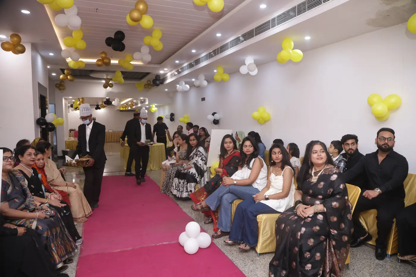 Guests seated along a red carpet in the decorated banquet hall