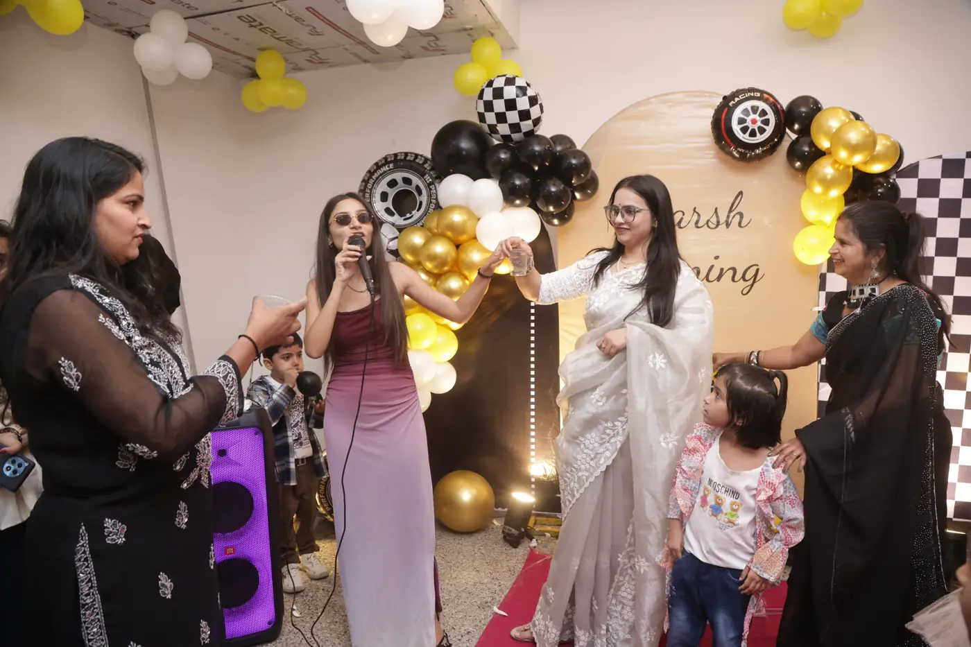 Guests singing together beside a colourful balloon backdrop