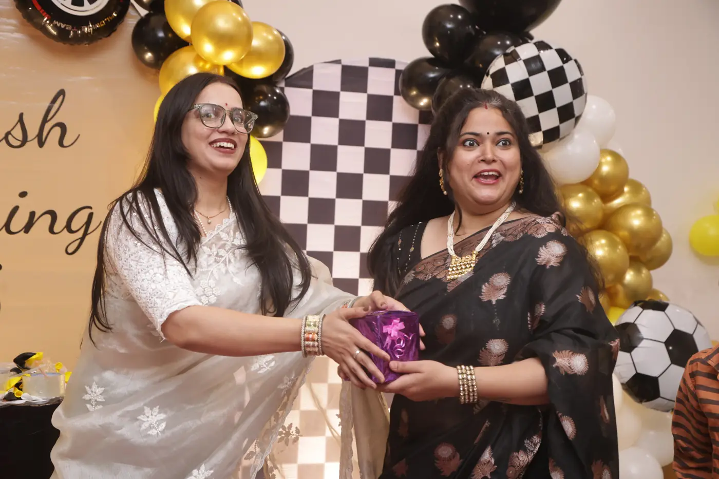 Two guests laughing as they exchange a gift