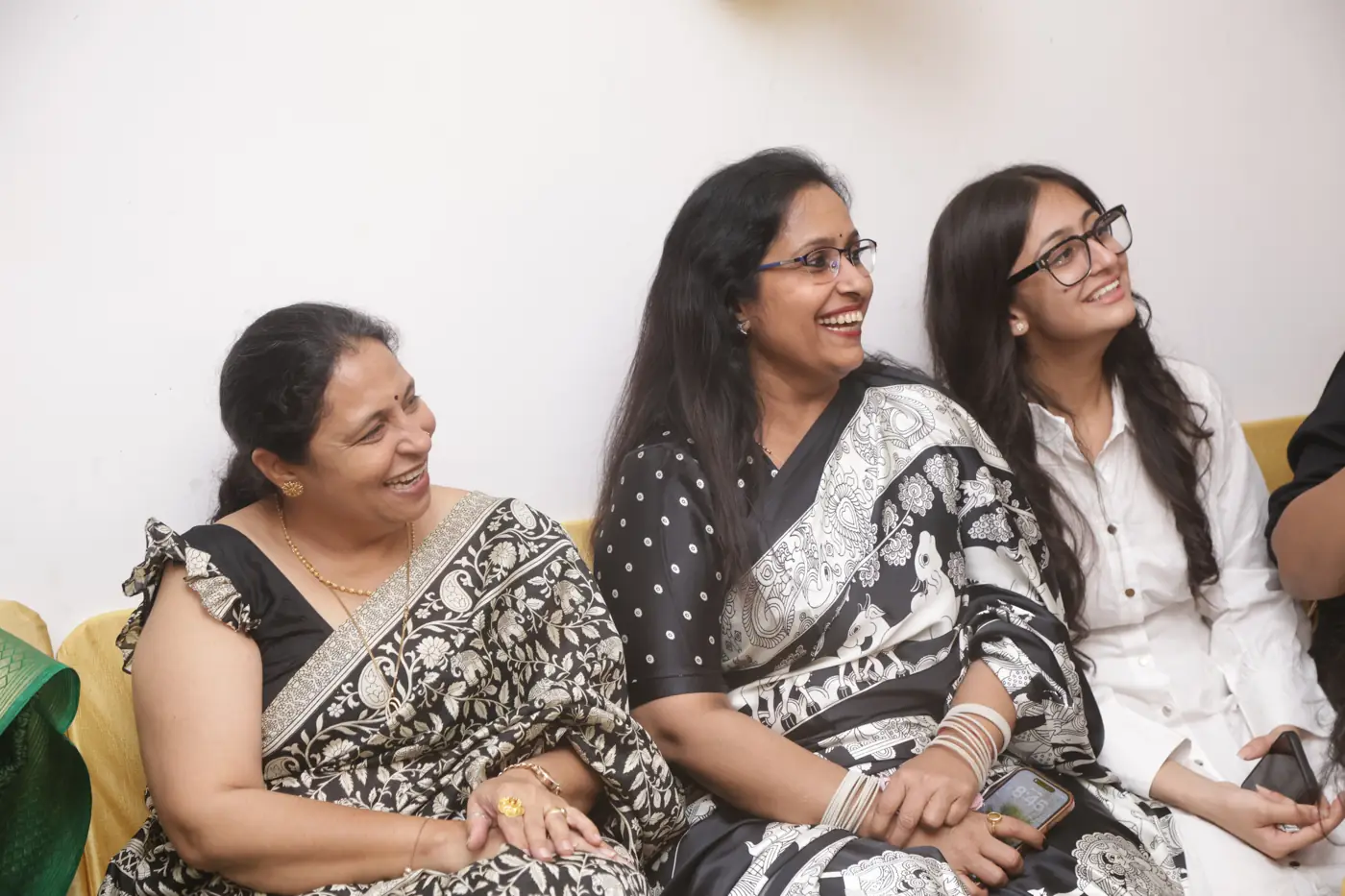 Three women seated together and smiling
