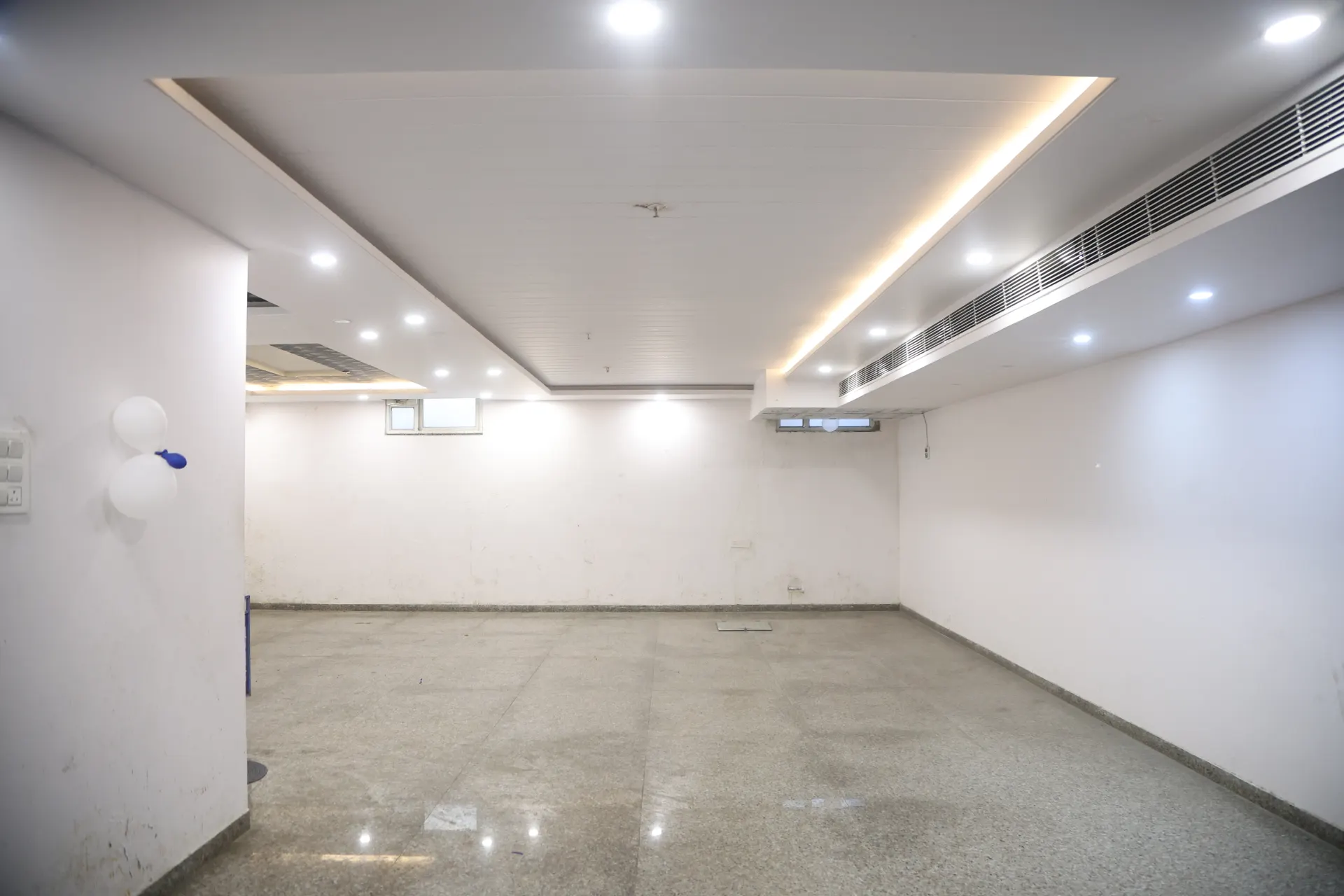 Bright, empty banquet hall with cove lighting and polished stone floor