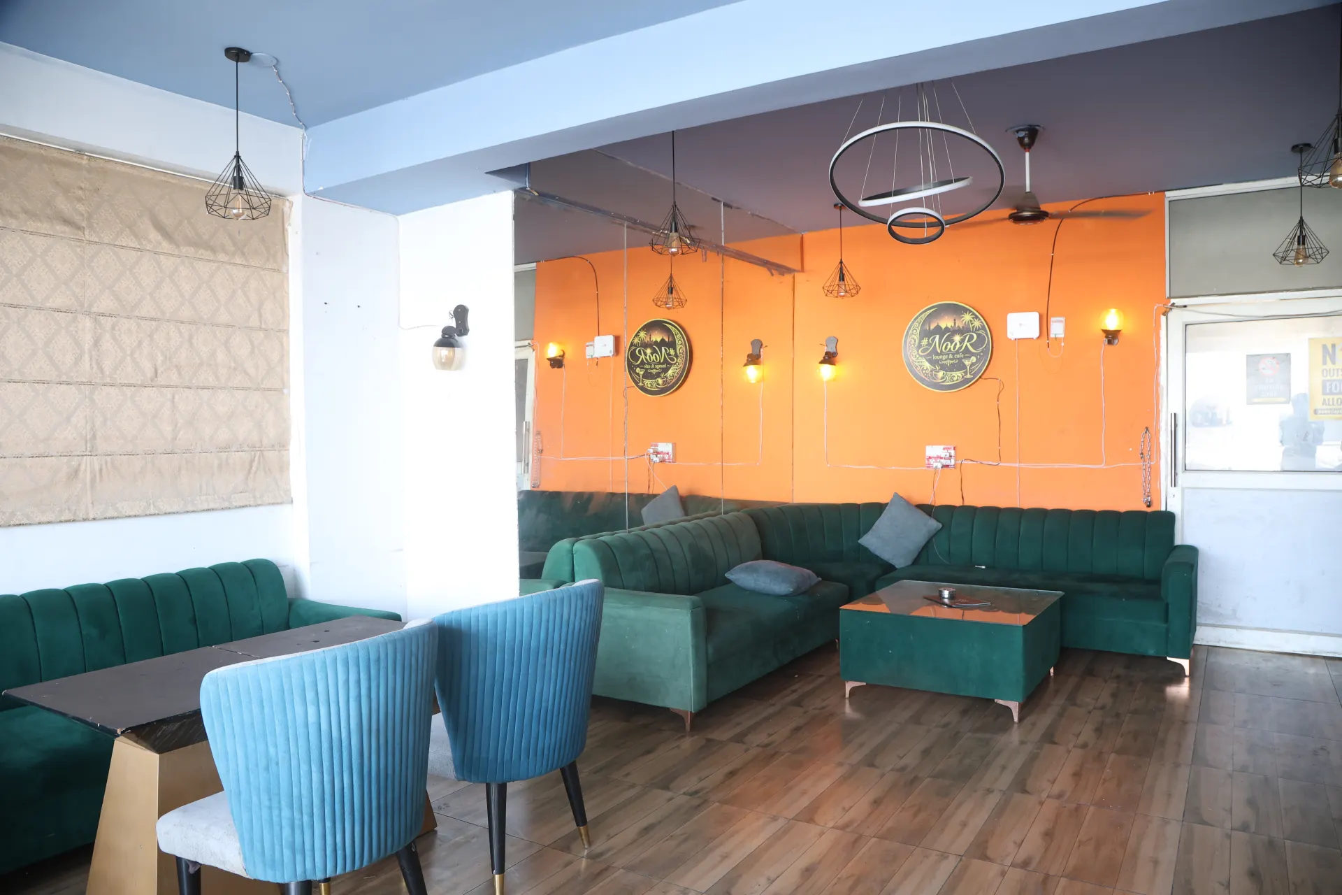 Rooftop lounge with an orange feature wall and teal sofas